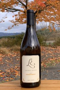 A bottle of Laurel Ridge Chardonnay pictured in a fall landscape with orange leaves and trees